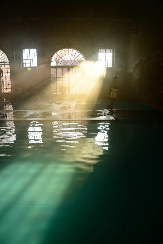 An image of water, with sunlight flooding in from a window and creating turquoise shapes on the surface.