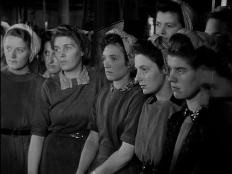 A black and white photo from the early 20th century. A group of young women in work clothing, their hair tied back.