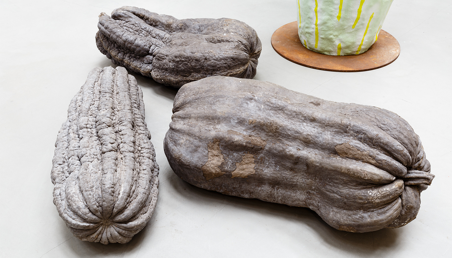 A series of three sculptural gourds arranged together. They are grey in colour, with hints of orange and peach.