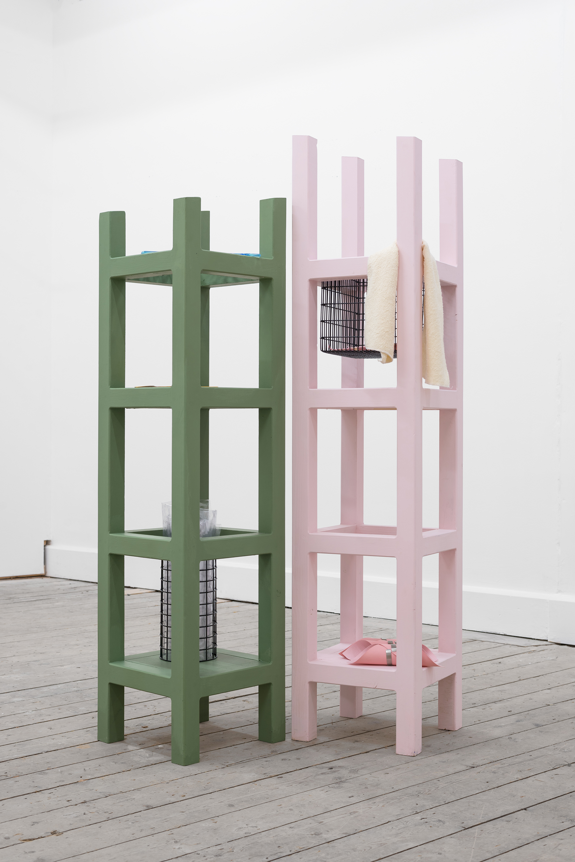 A sculpture that looks like two sets of shelves, one in green, the other pale pink. Some objects rest on the shelves.