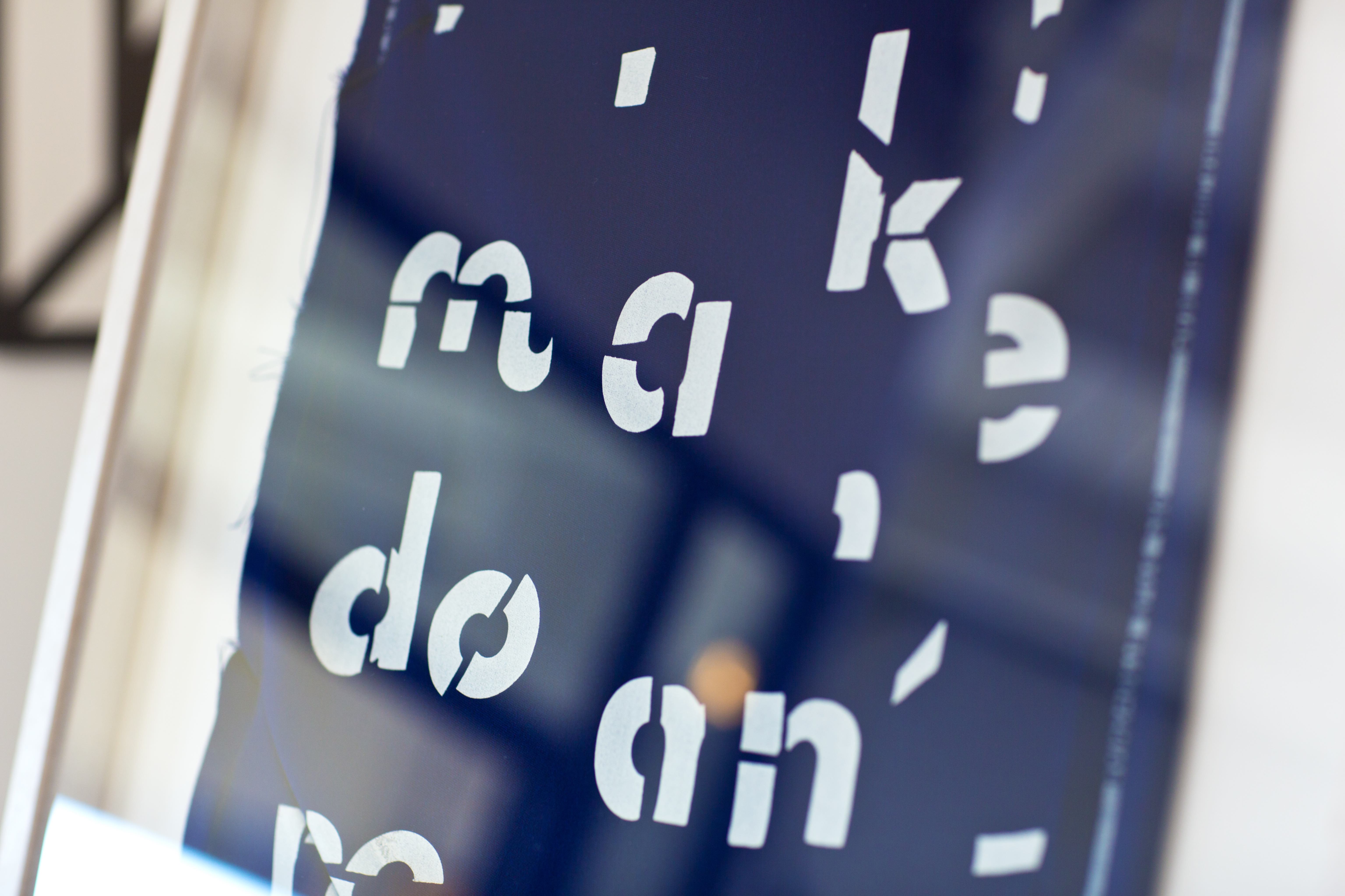 A close up of a print in dark blue, with fragmented letter forms in white.