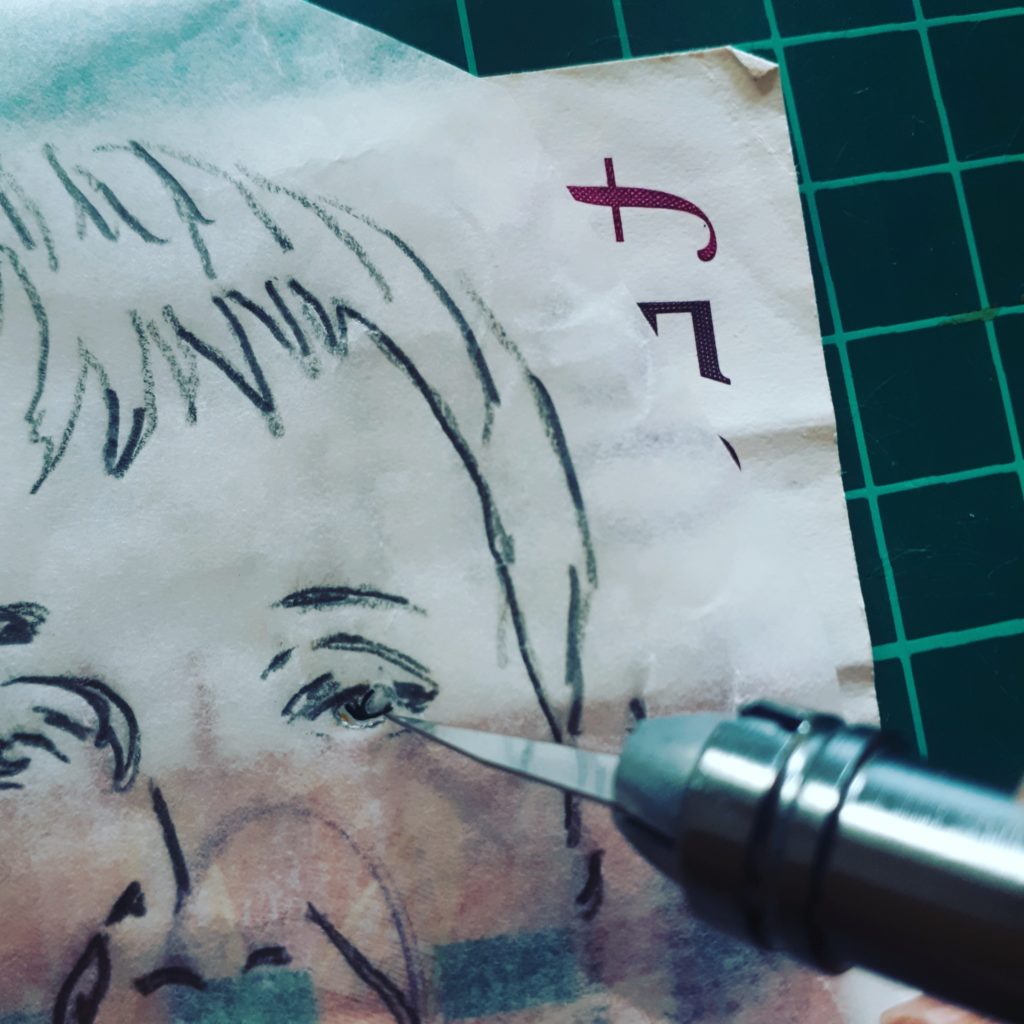 A close up of a scalpel cutting into a drawing of a face on tracing paper laid over a 50 pound note.