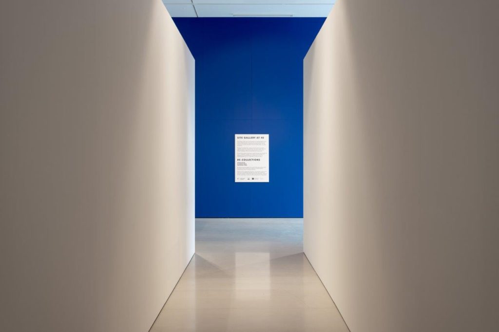 A view of a gallery corridor, with a bright blue wall at the end.