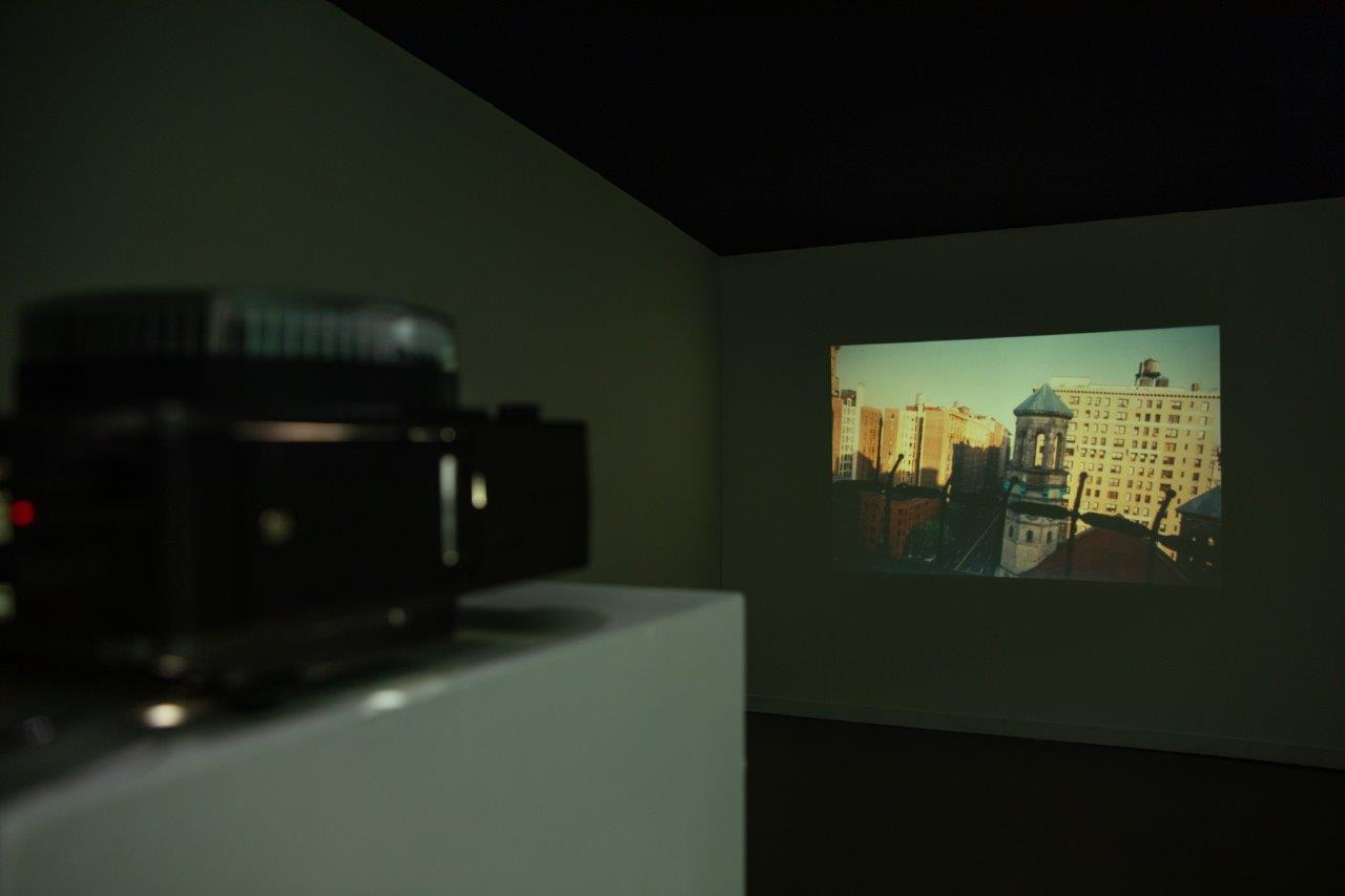 A slide projector in a dark room, showing images of a cityscape.