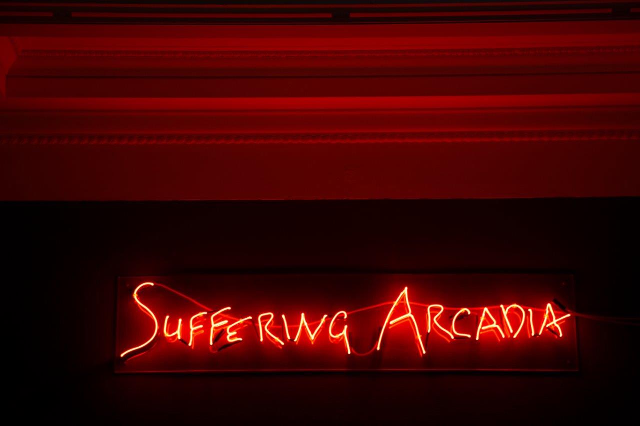 Neon red writing that reads: 'Suffering Arcadia'.