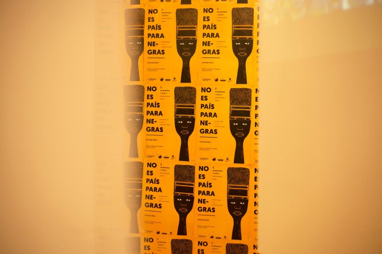 A repeating line of posters, in yellow and black, advertising a play 'No Country for Black Women'.