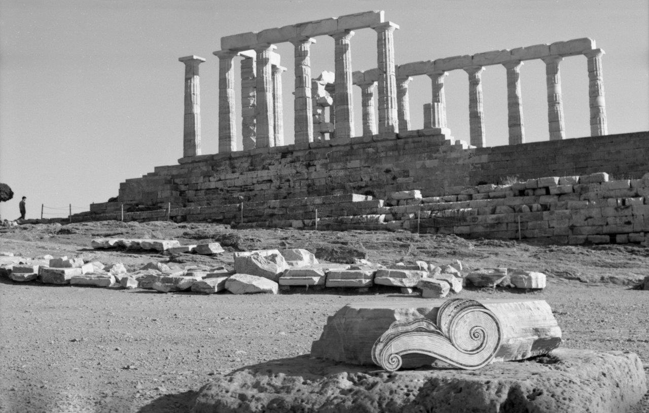 A black and white image of an ancient ruin, with a curled detail added in the foreground.