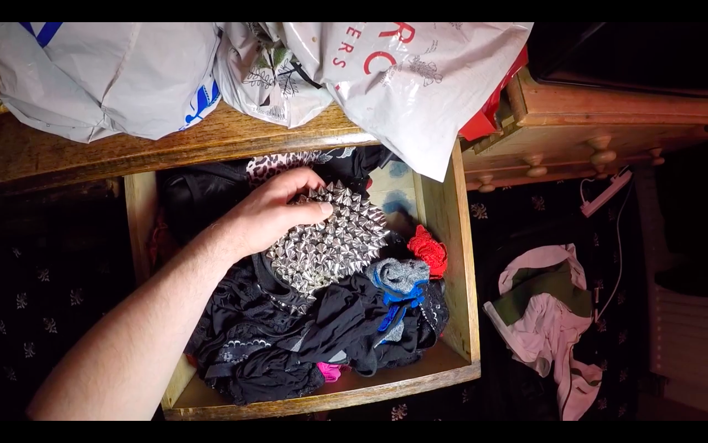 A hand reaches into a drawer of fabrics, holding a small item made from black fabric with metal studs.