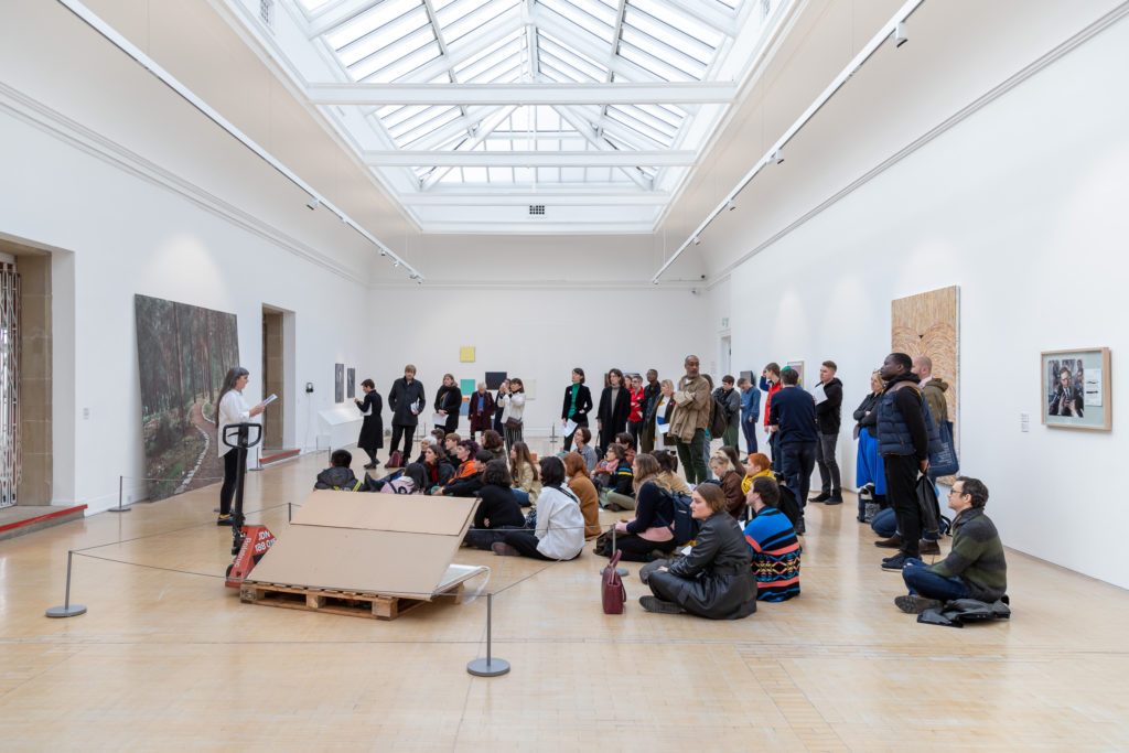 People gathered in a light-filled gallery for a performance.