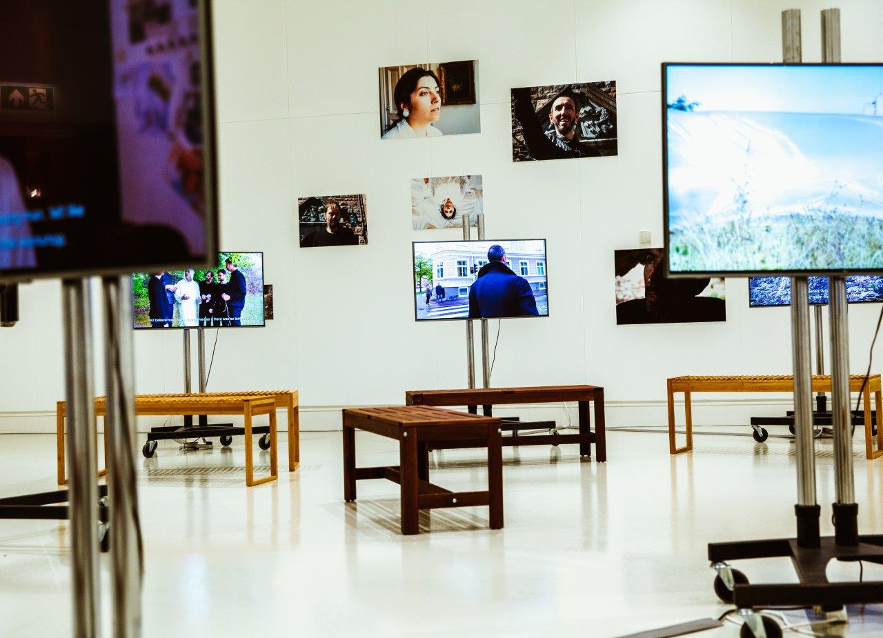 A view of a gallery filled with TV screens and benches.
