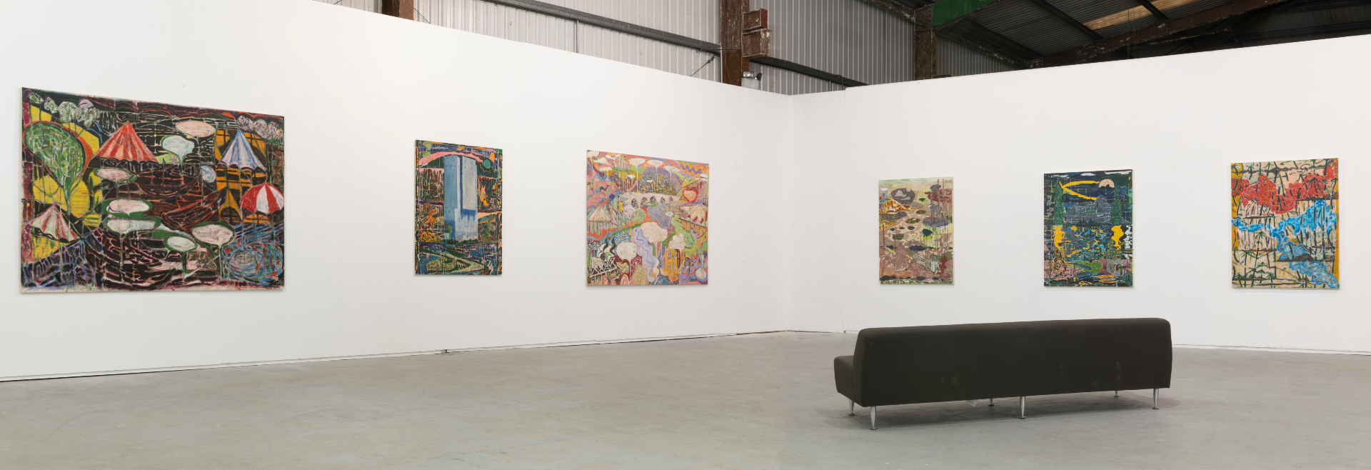 photograph of white-walled gallery space with a black sofa face six paintings
