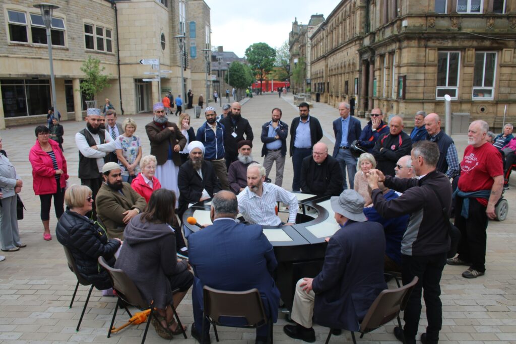 A group of people conversing in a circle, in a city square