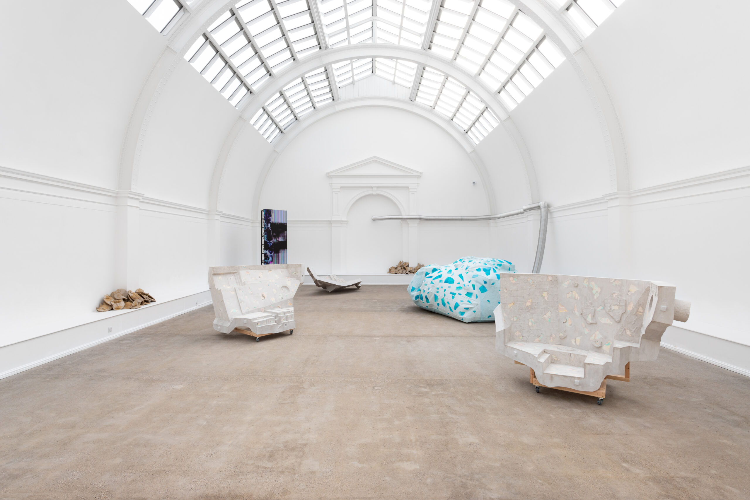 An image showing the full installation from a central perspective, with a grouping of sculptures and a clear view of the glass ceiling.