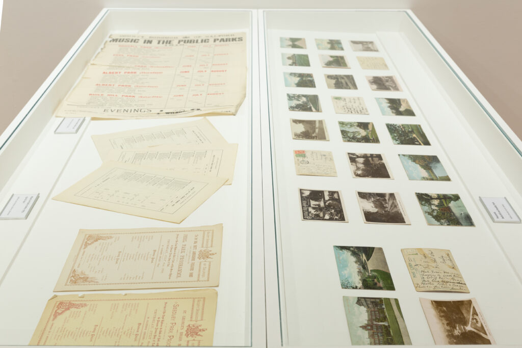A glass vitrine is shown, holding archival documents and images relating to music and bandstands in parks.
