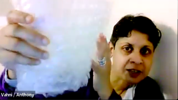 A still of a video of artist Vahni Capildeo holding up a piece of bubble wrap to the computer camera