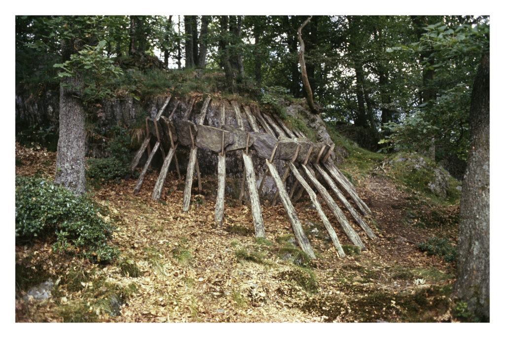 A structure built of wooden logs and pieces of stone in a forest