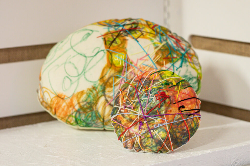 Two soft looking round sculptures made of multicoloured textiles