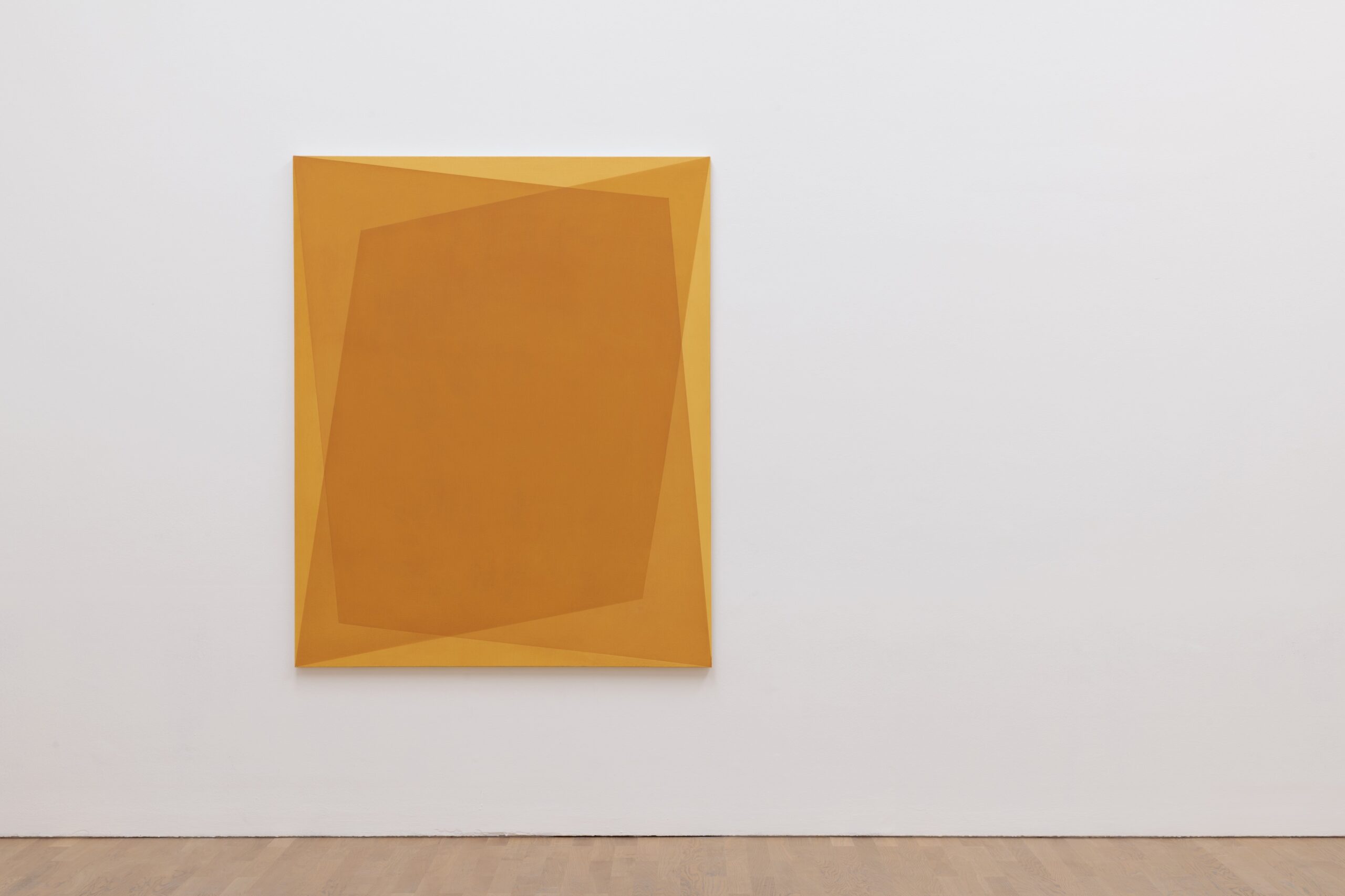 A three-tone ochre geometric painting on canvas hangs on a white wall.