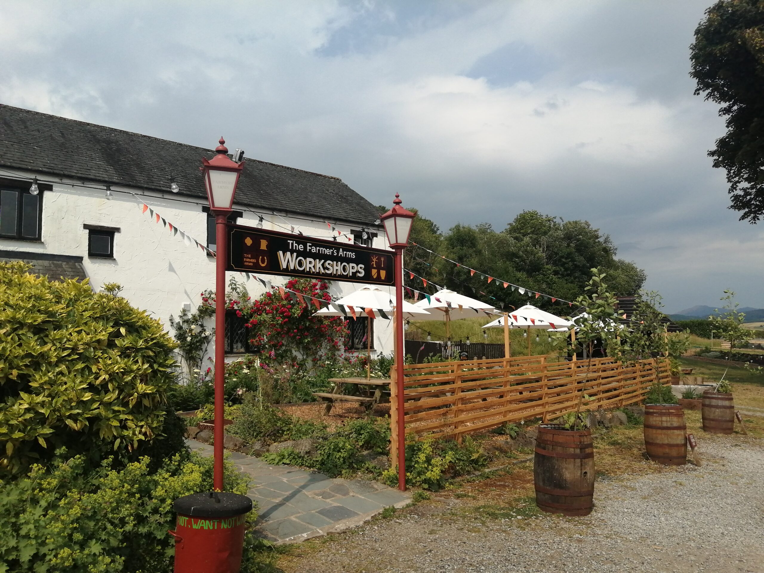 Photograph from the car park outside The Farmer's Arms showing a sign saying 'Studios' and the white farm building