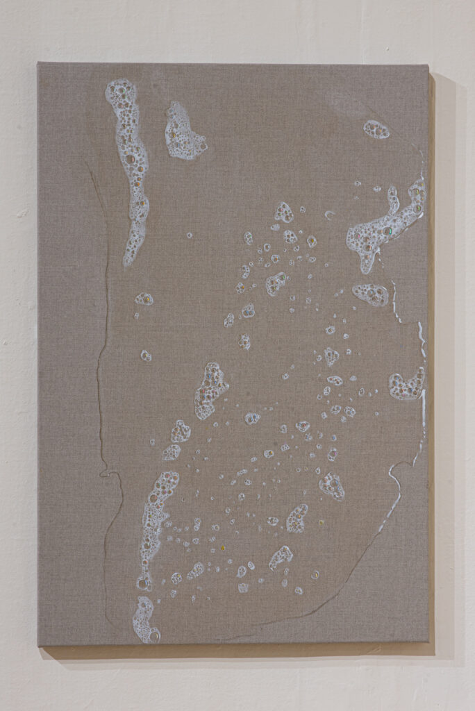 A close up view of the painting which looks like a pool of soapy water has really been spilt on the brown canvas, with clusters of white bubbles dotted about.