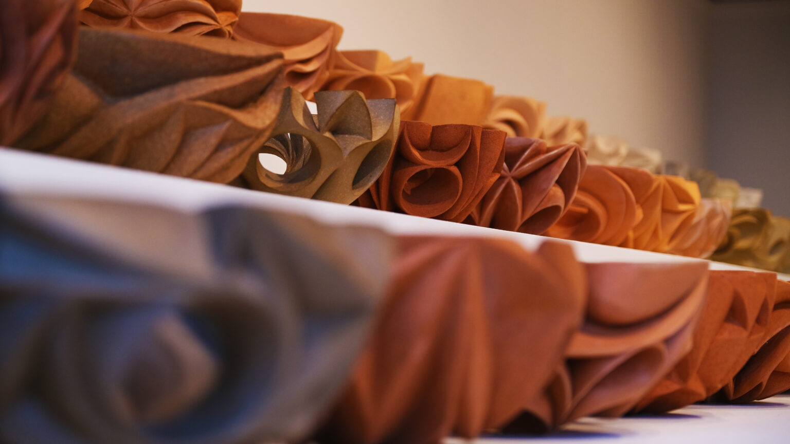 A close up of the sculptures in rows, so the bottom left is very dark grey and blurred and the colours get brighter and the image sharper up to the top right.