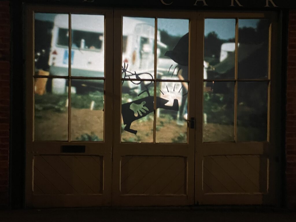 A video projection is viewed through window panelled external doors.
