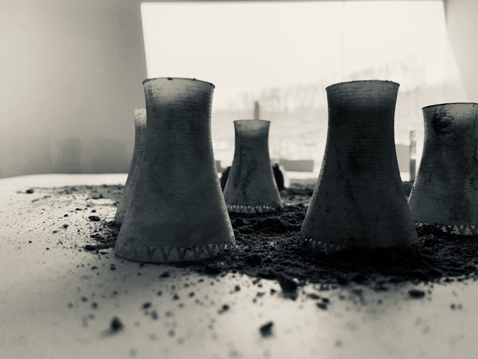 Silhouettes of model cooling towers, dark against projected white image on wall behind.