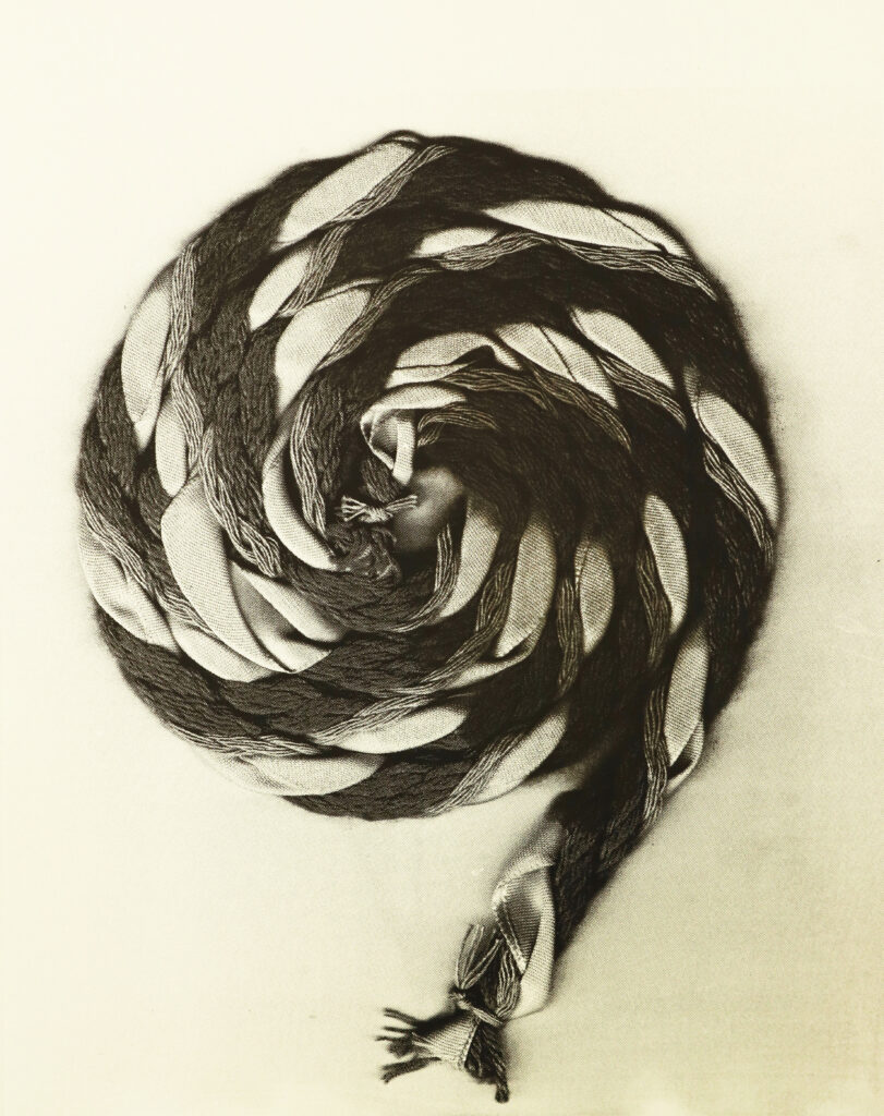 A black and white image of a plaited cord wound into a tight coil