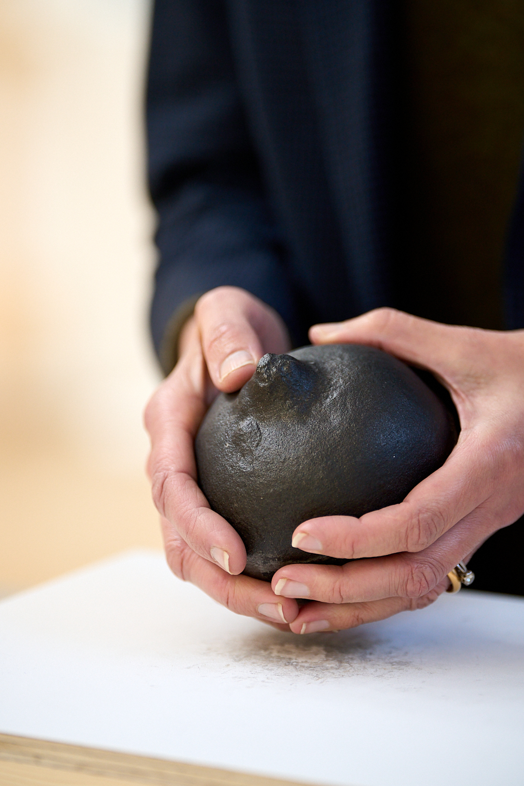 A person in a black shirt handles a life-size pomegranate cast in iron.