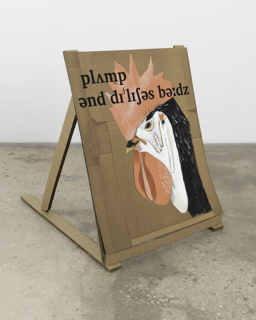 A cardboard sign with confusing lettering and the image of a cockerel's head