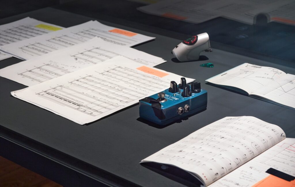 A display of printed out sheet music with hand written notes and a pieces of music equipment