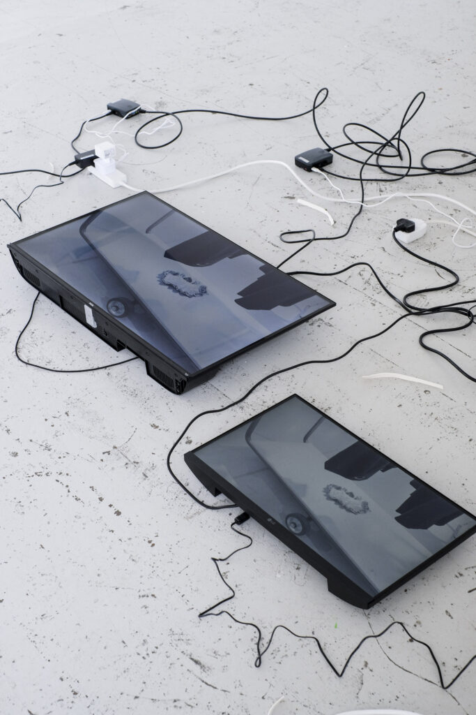 Two TV monitors laid flat on the floor with cables zigzagging around them