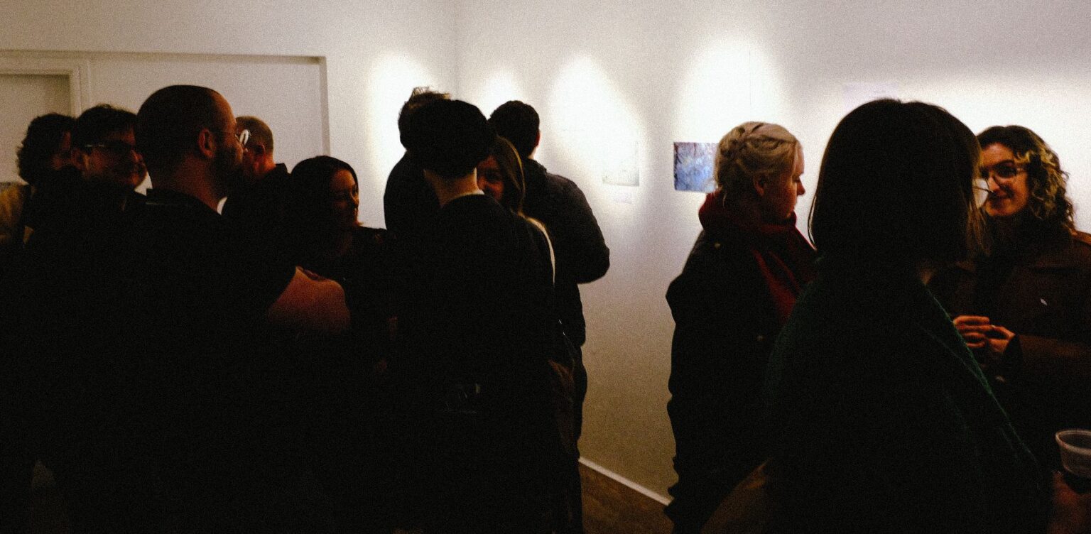 Dark image of a party with low lighting showing prints on walls