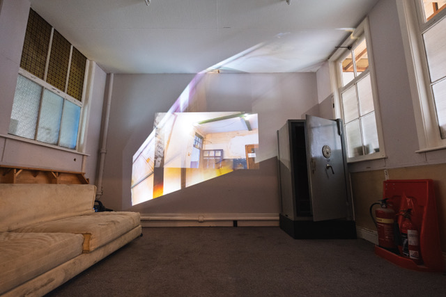 Brightly coloured projections of the interior of a room with painted doors and window frames projected on a wall